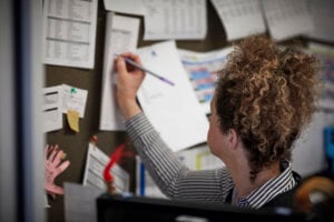 A woman writing notes in the school office.