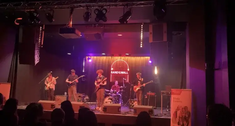 A band on stage, performing with drums and guitars.