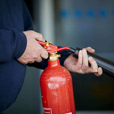 a man holding a fire extinguisher and pointing it at something off camera