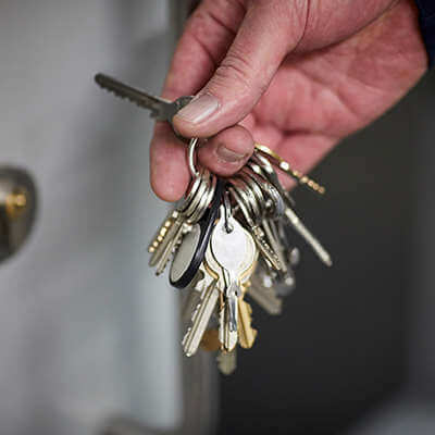 A mans hand holding a bunch of keys next to a door