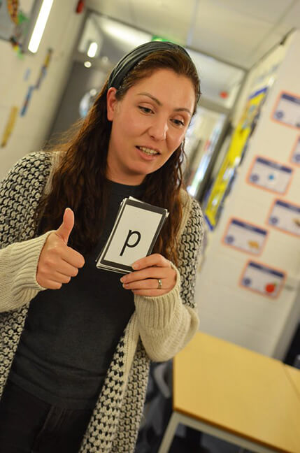 teacher holds up phonics card primary school