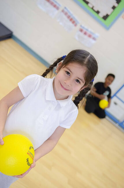 girl pupil holding a ball in sports hall
