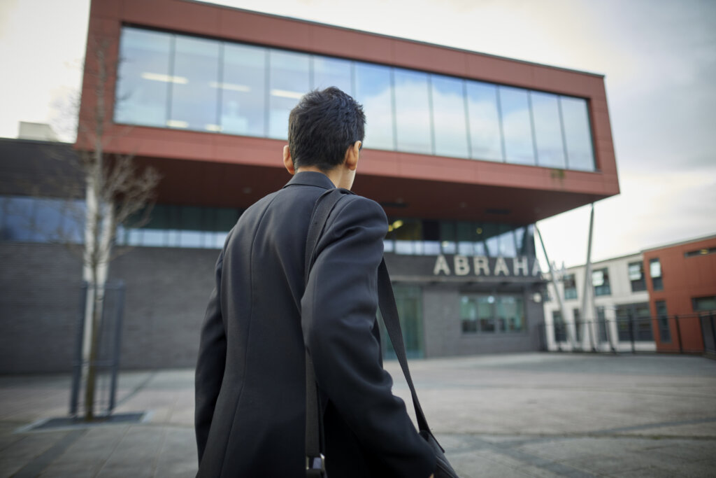 A secondary school student outside the school building.