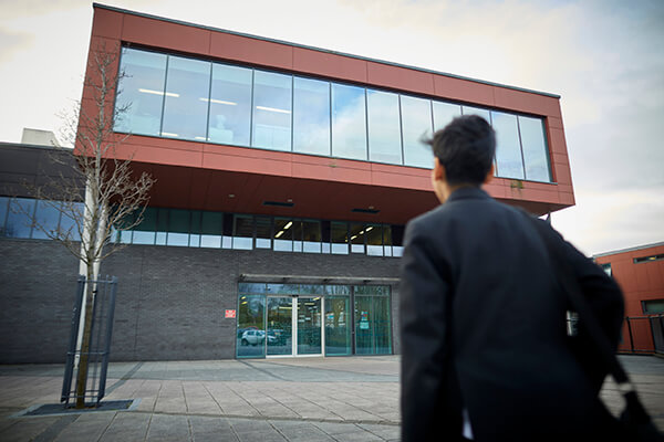 A secondary school student walking towards the school building.