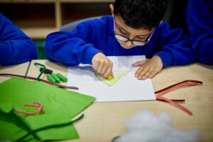 A schoolboy colouring a yellow triangle.