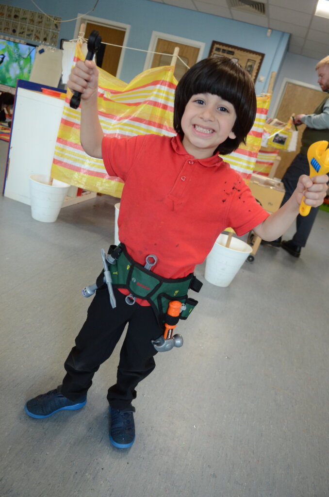 pupil boy holding up play tools in EYFS classroom