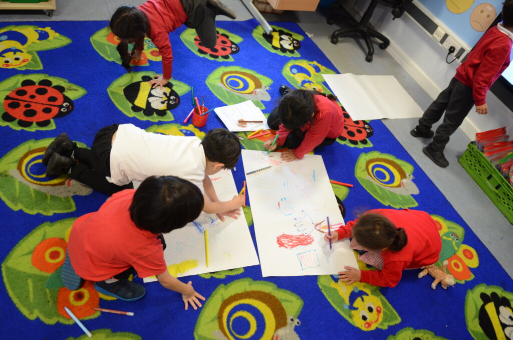 Children drawing on the classroom floor