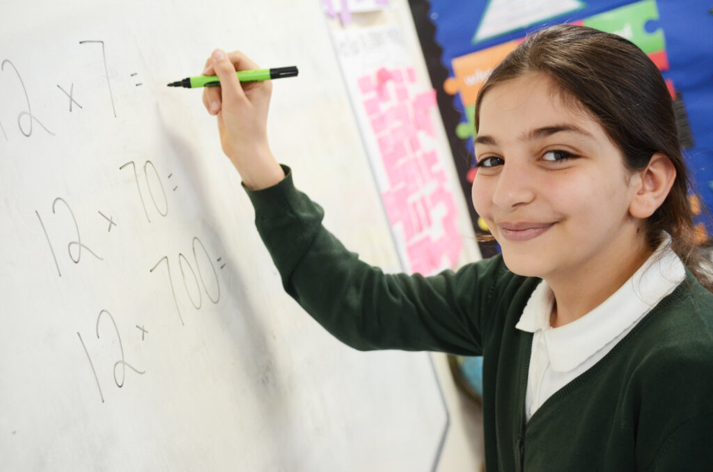 girl pupil smiling and writing on whiteboard