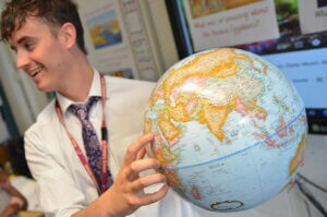 A teacher pointing at a globe in school.