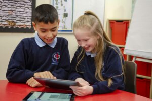 boy and girl pupil share iPad
