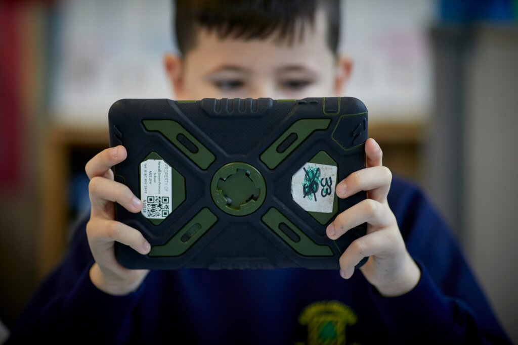 A young boy holding a tablet with both hands.