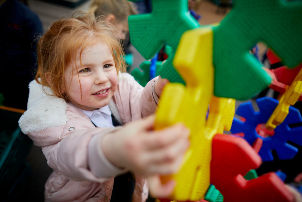 A girl playing with colourful outdoor equipment.