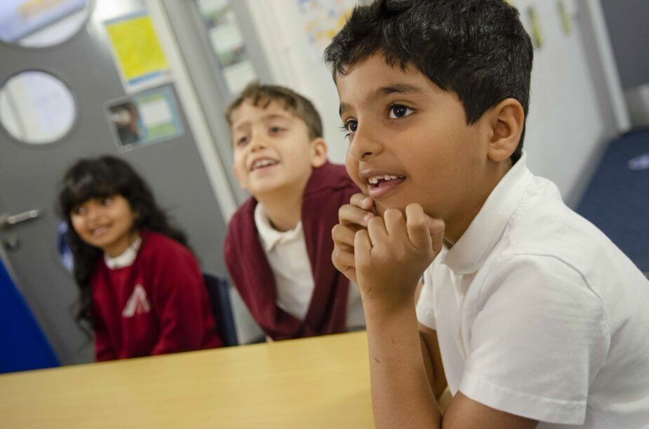 Young children sitting around a table and smiling.