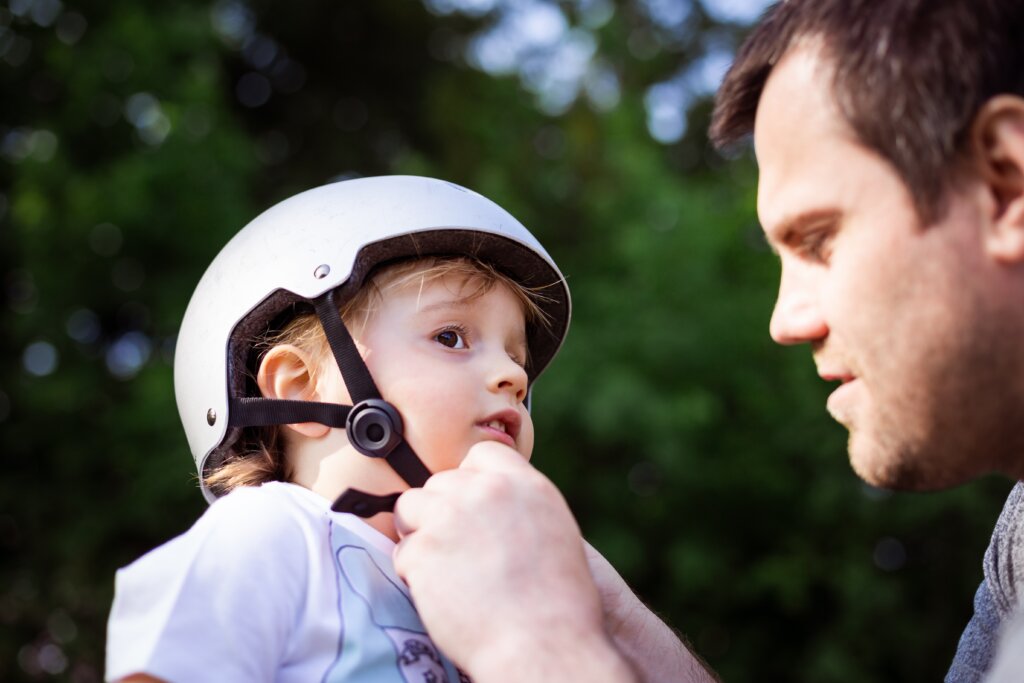 A father putting a safety helmet on his child