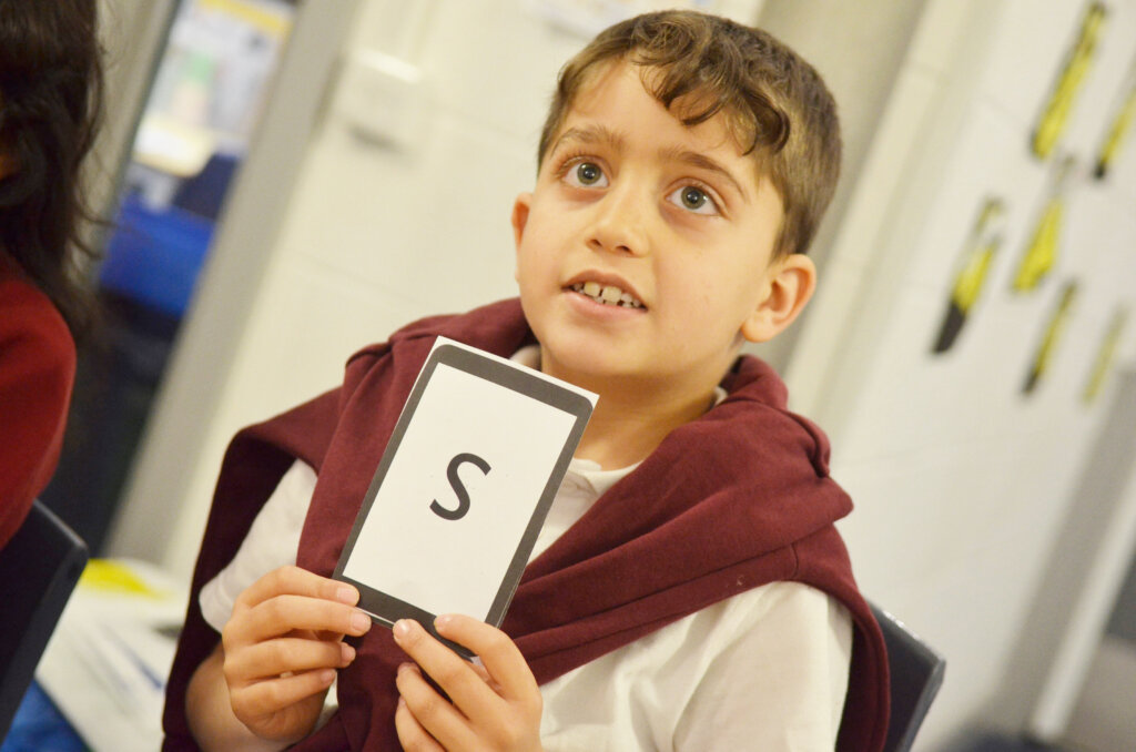 boy pupil hold up letter