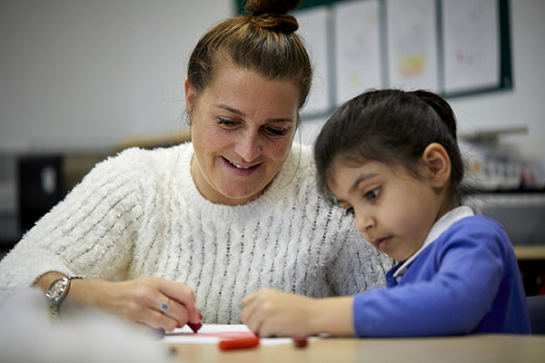 A teacher and early years pupil colouring in together.