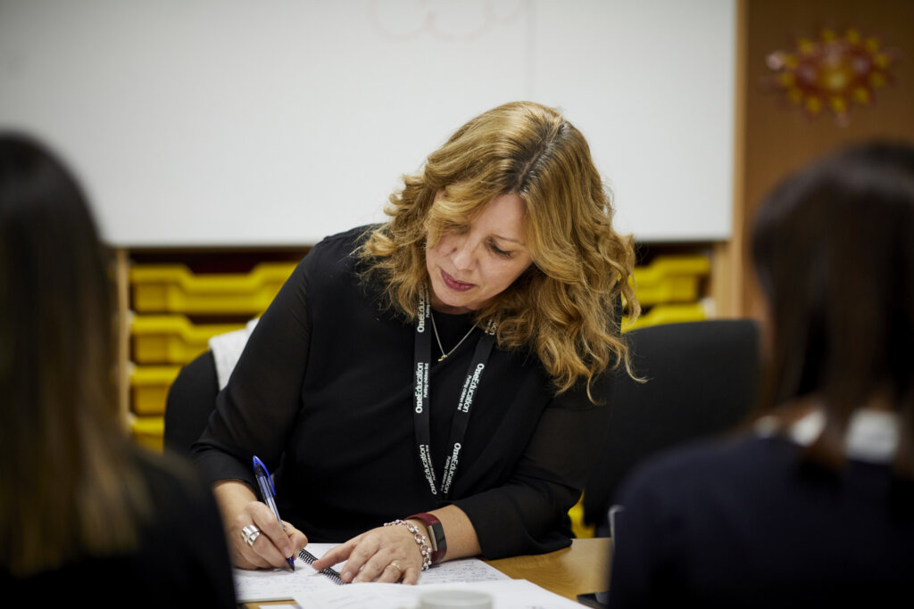 A woman writing notes at a staff meeting.