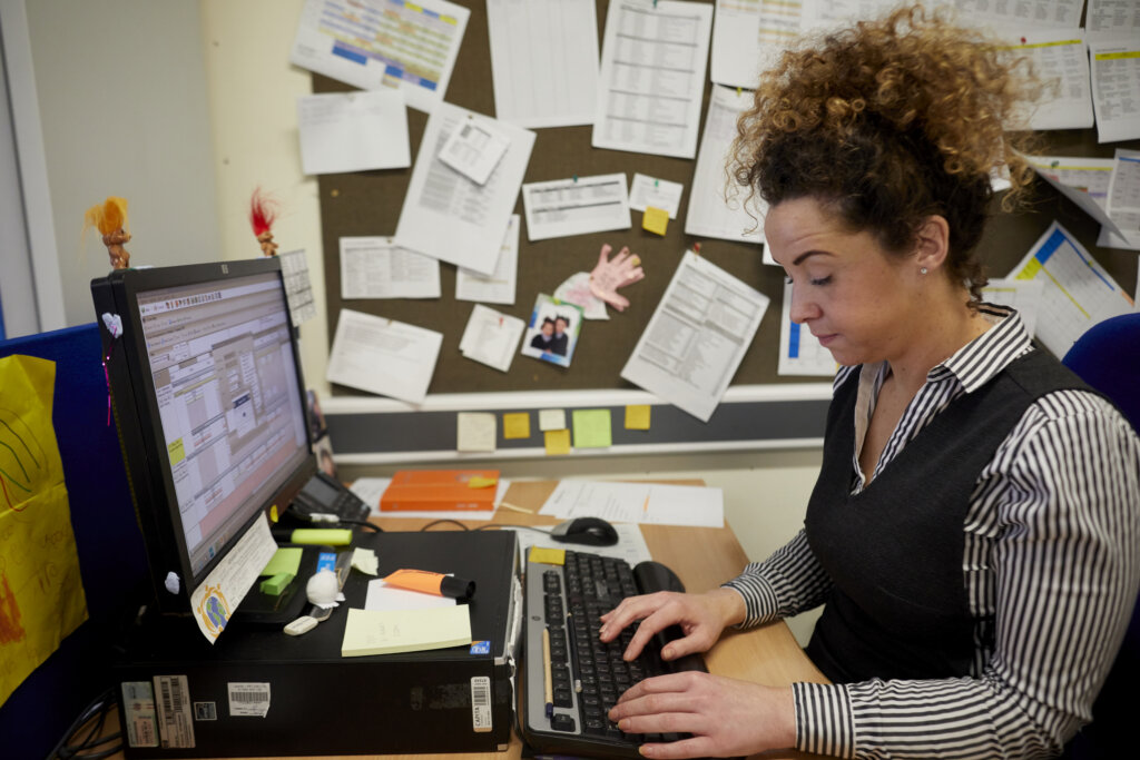 A woman in the school office, working on the computer.