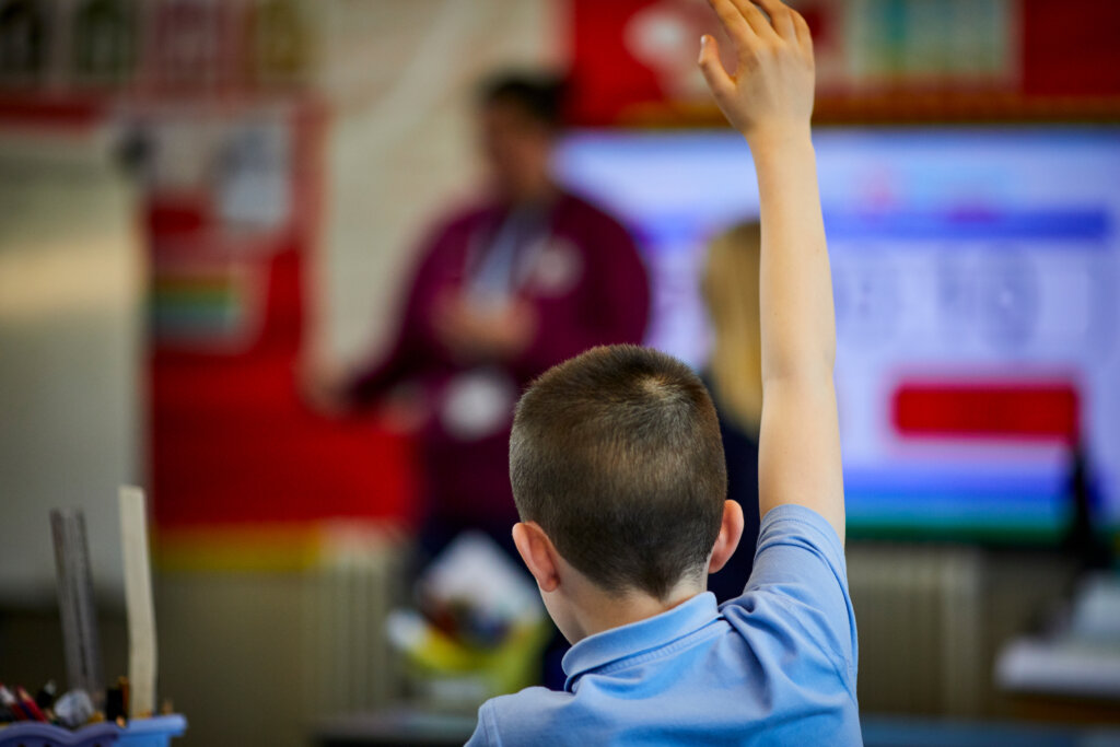 A boy raising his hand in the classroom.