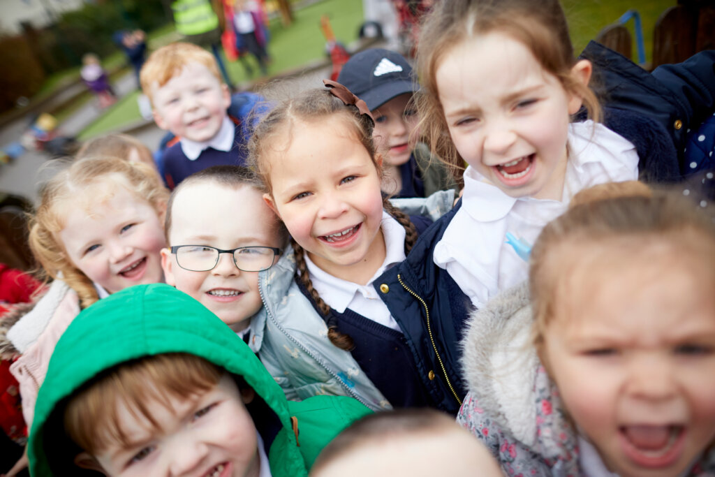 A group of children in the playground, smiling.