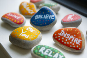 Stones painted with colours and decorated with inspirational words and phrases