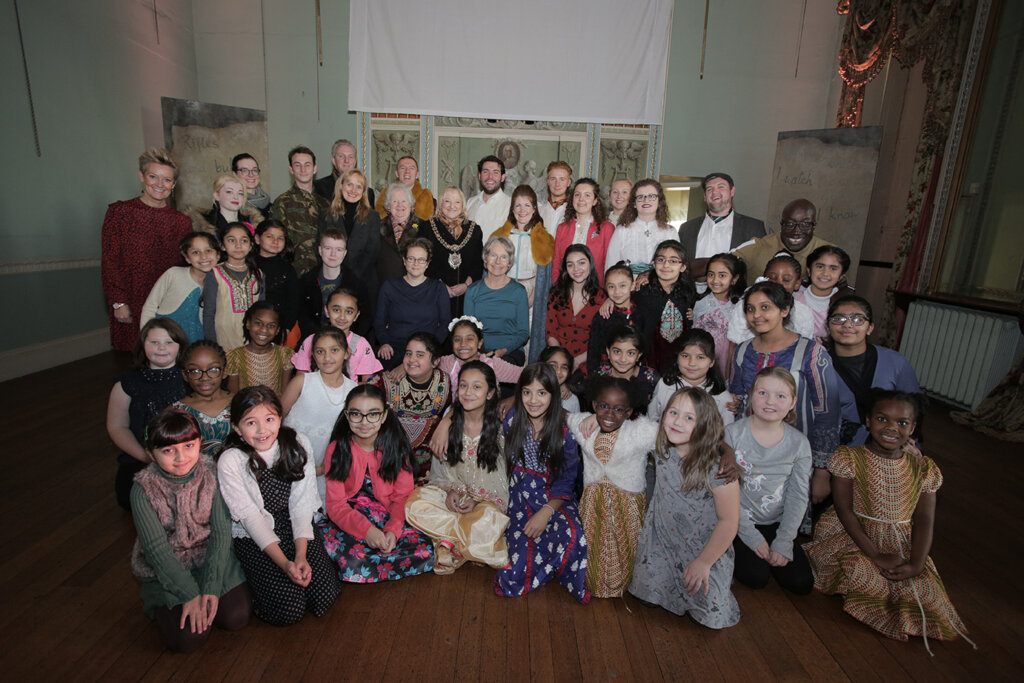 Pupils from the choir standing in the school hall and smiling at the camera.