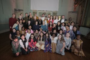 Pupils from the choir standing in the school hall and smiling at the camera.