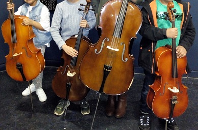 Students standing with their cello instruments.