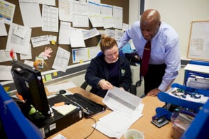 A man and woman looking at paperwork in the school office.