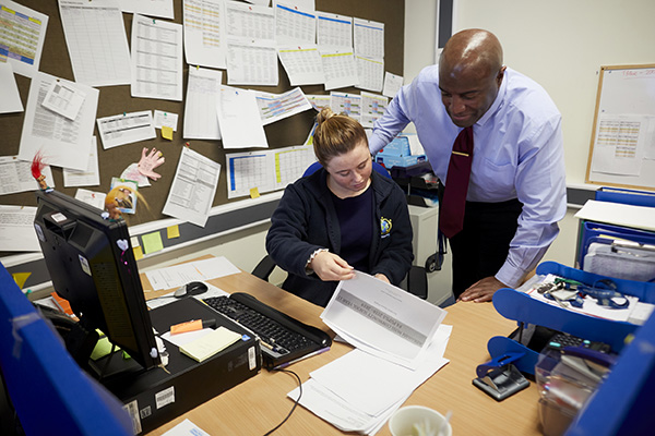 A man and woman looking at paperwork in the school office.