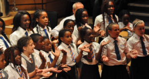 A group of students singing together and using hand movements.
