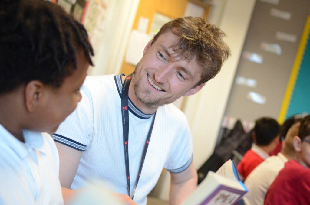 A male teacher smiling at pupil.