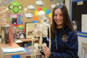 A teacher holds a human skeleton model as she delivers a lesson in the classroom.