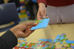 Two hands, passing a jigsaw piece between them