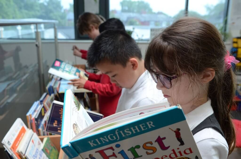 A girl and a boy reading books in the school library.