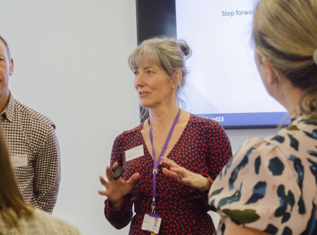 Jeni stands in front of a screen as she delivers a workshop to delegates.