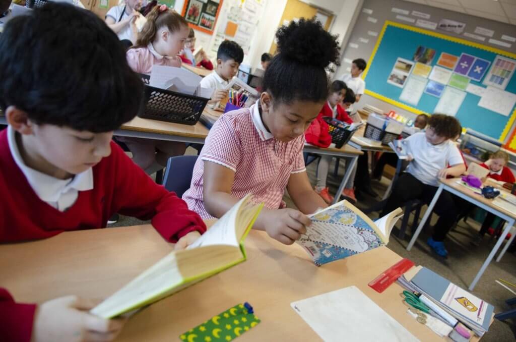 Children reading books at their desk in the classroom.