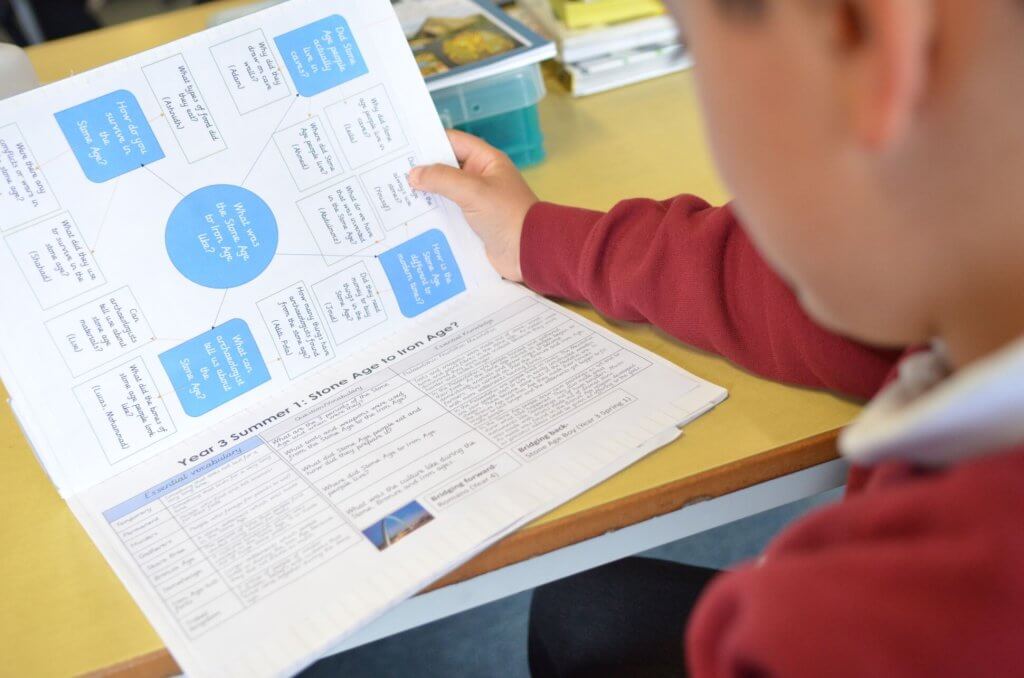 A child holding open the pages of his workbook.