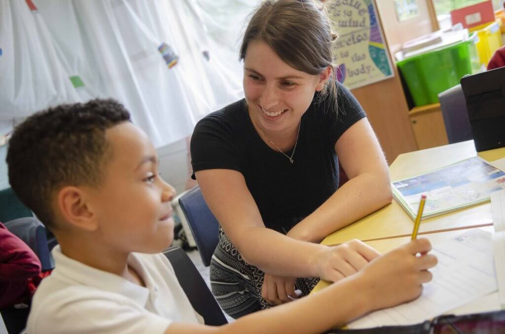 A teacher and pupil working together on a piece of work in the classroom.