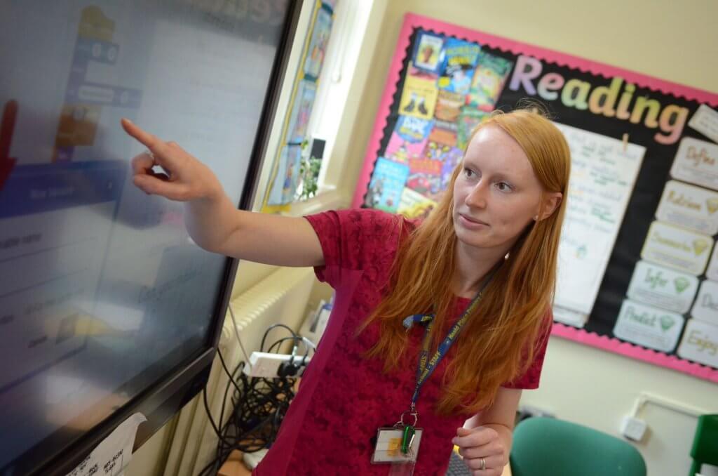 A teacher pointing to the whiteboard in class.