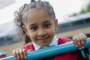 A pupil in the playground, smiling at the camera.