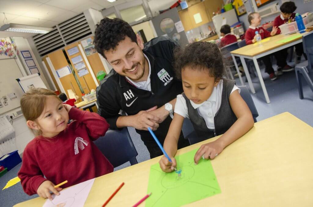 A teacher supporting two children in the early years classroom.