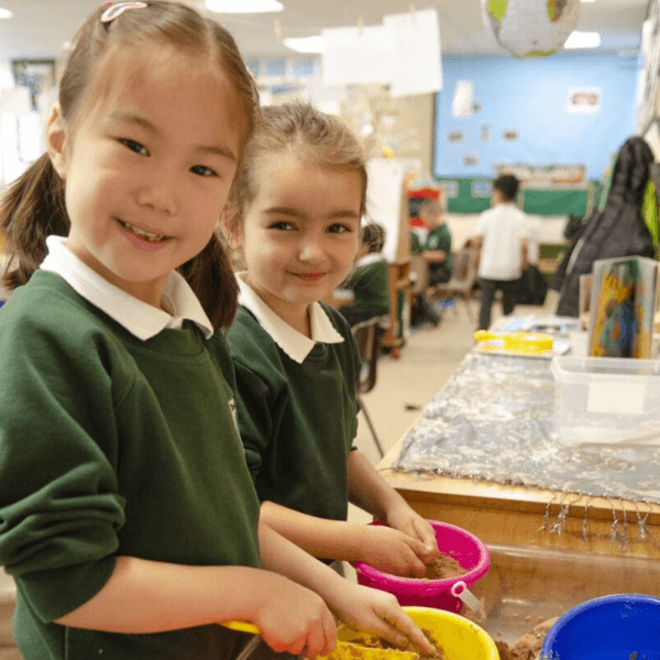 Two girls in the early years classroom playing in the sandpit.