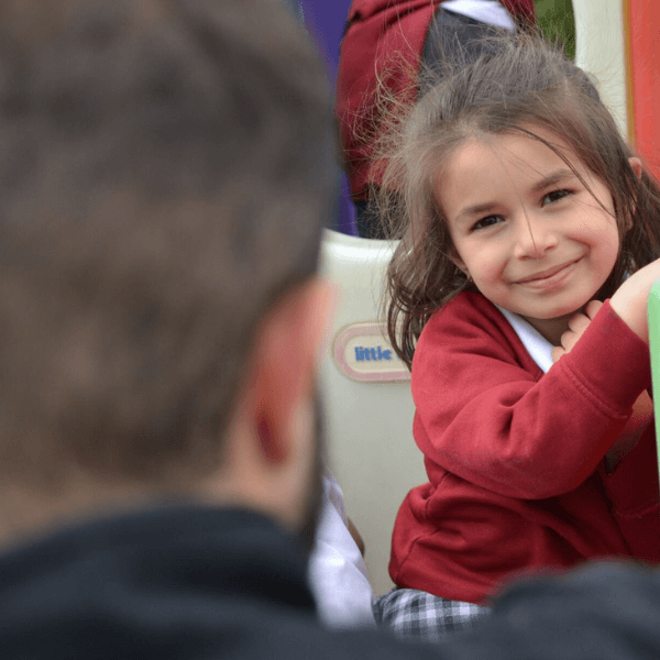 An early years pupil smiling towards her teacher. 