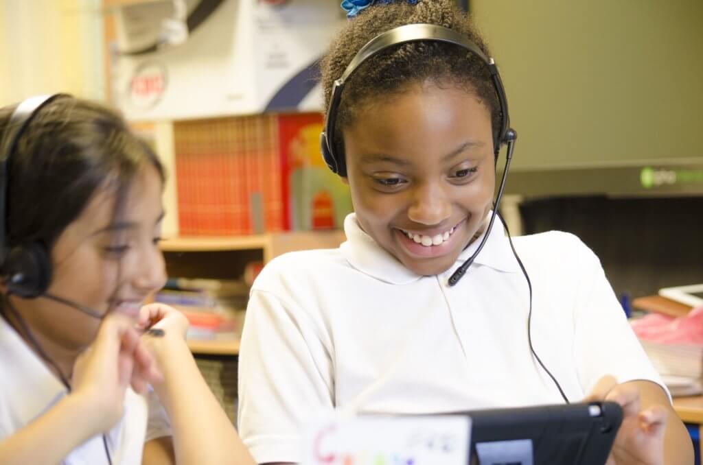 Two pupils wearing headsets and smiling.