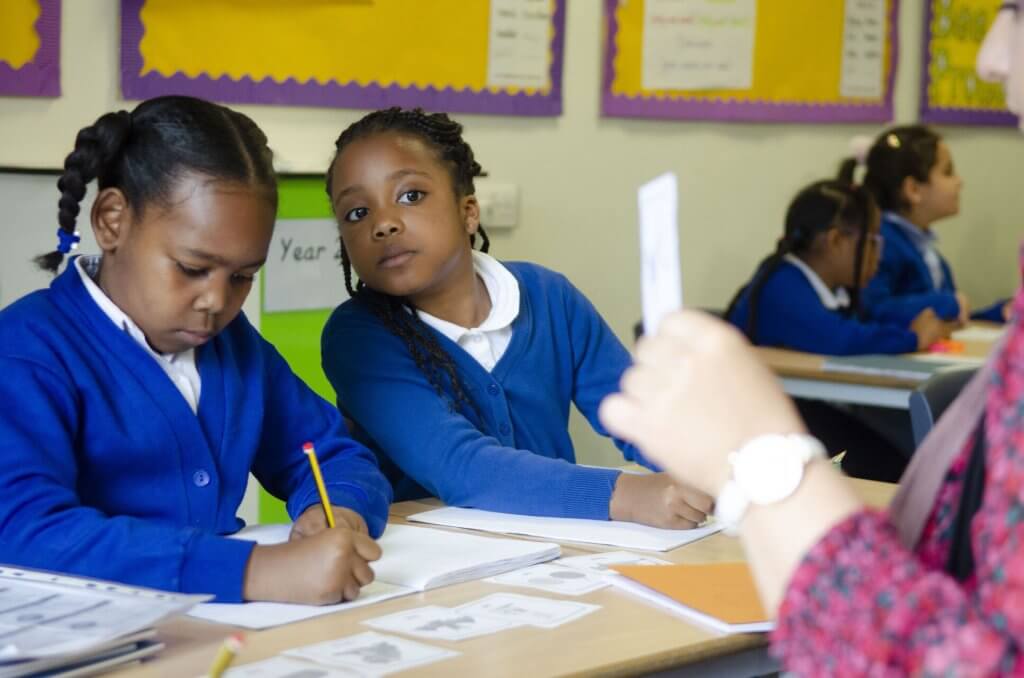 Two school children writing at their desk.