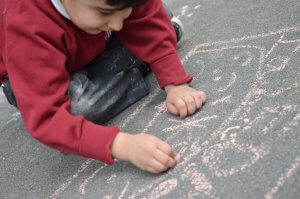 A child drawing with chalk on the playground