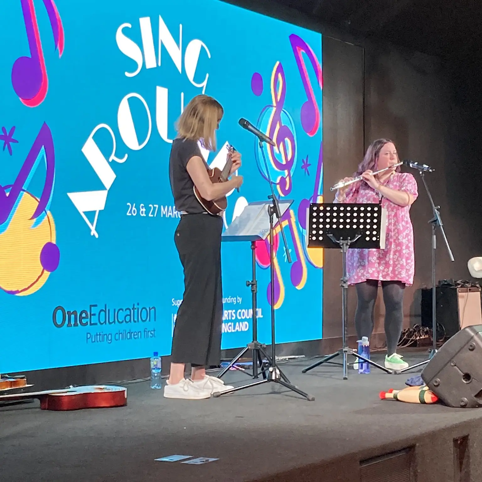 Jo Buckler and Jules Kent performing musical instruments on stage