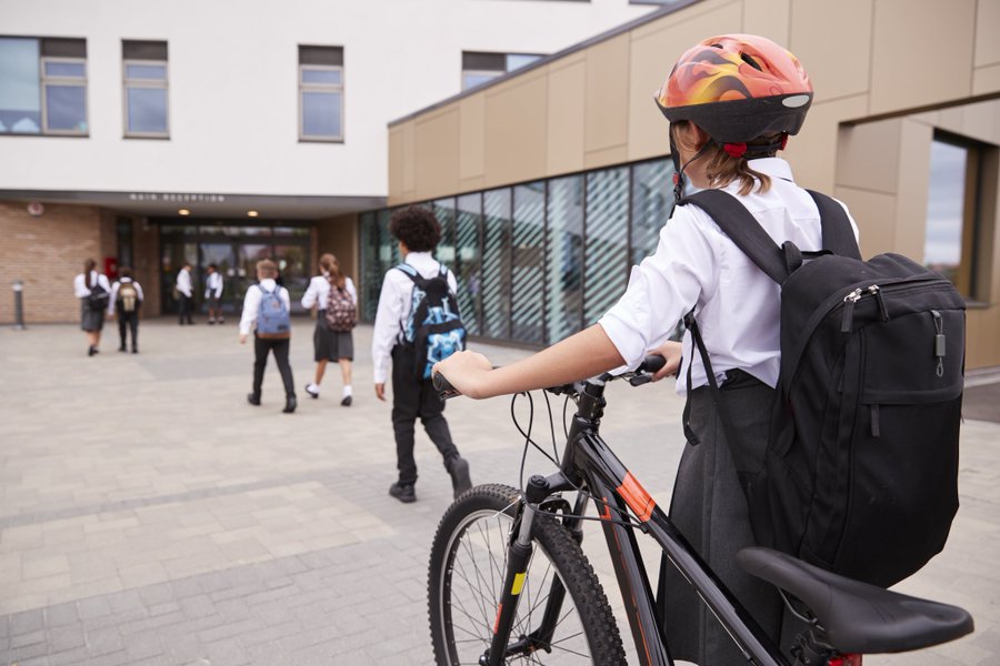 School child wheeling bike through playground