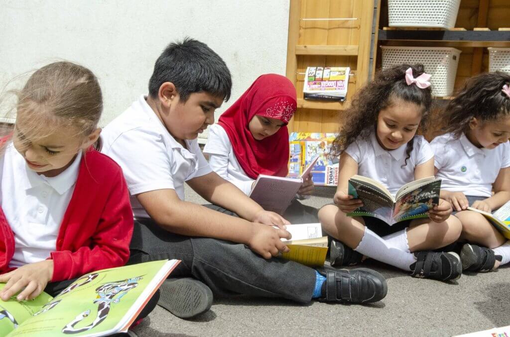 Children reading books in the playground.